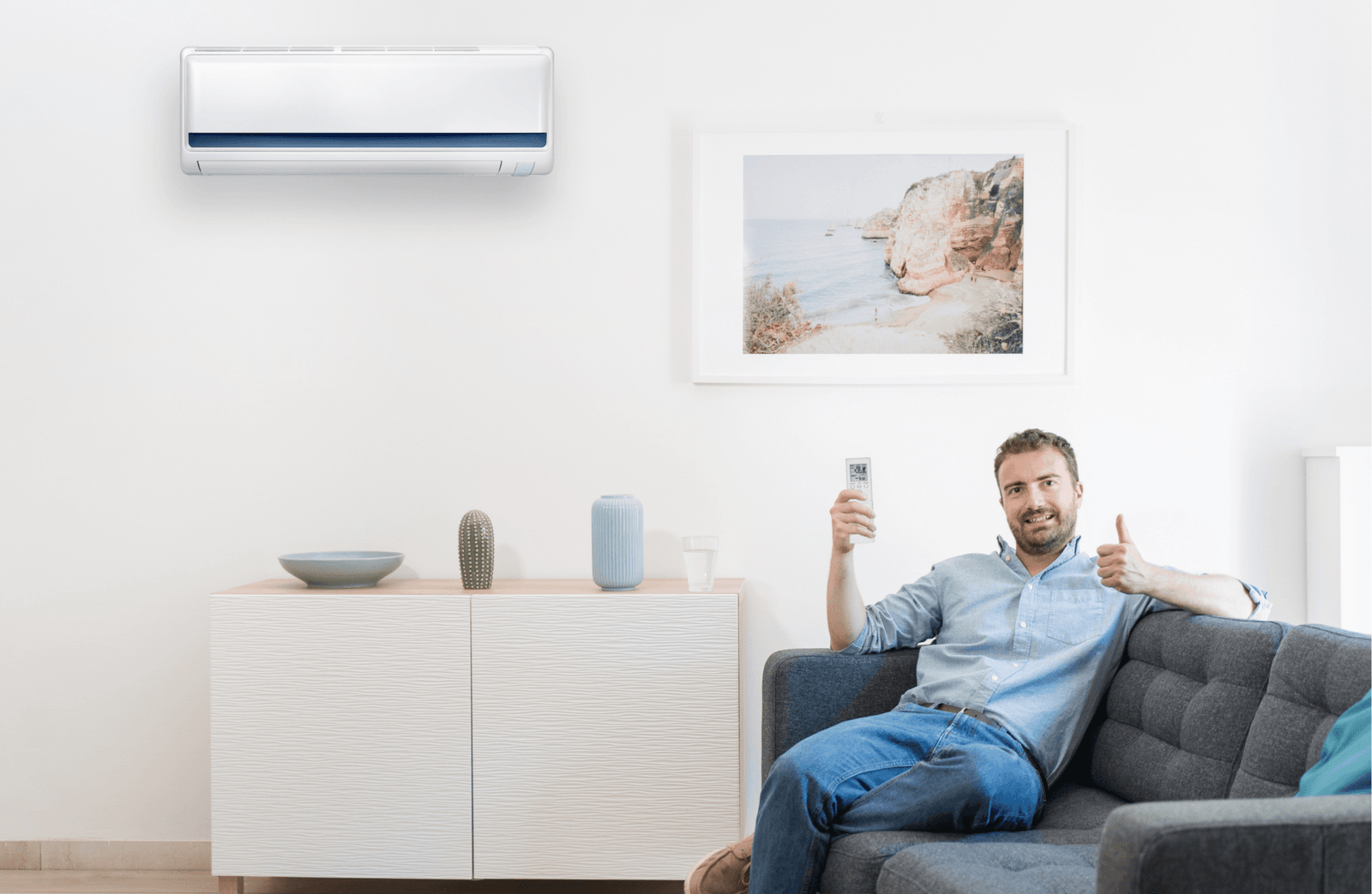 Man zit in de zetel met duim omhoog en afstandsbediening om airco mee te bedienen